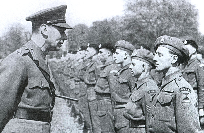 This is a photograph of HM King George VI speaking with a REME soldier at the parade of the 44th Regiment Royal Armoured Corp 22nd April 1944 